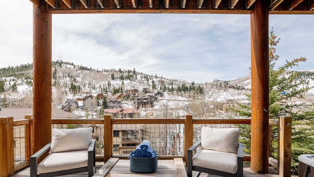 A wooden deck with two chairs and a table, overlooking a snowy mountain town. - Lower Deer Valley with Amazing Views, Private Hot Tub, Walk to Old Town (Park City)