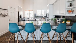 A spacious kitchen with white cabinets, a central island with bar stools, and a view to the backyard. - Lower Deer Valley with Amazing Views, Private Hot Tub, Walk to Old Town (Park City)