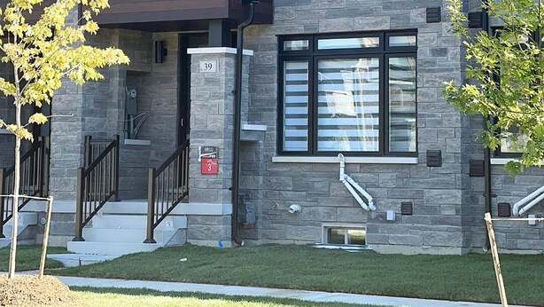A multi-story residential building with a stone facade, large windows, and a visible entrance with a mailbox.