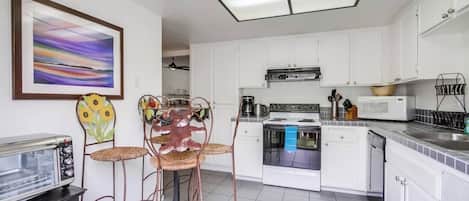 Eine moderne Küche mit weißen Schränken, einem Gasherd, einer Mikrowelle und einem Toaster.
