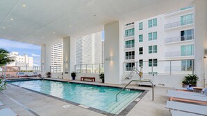 An indoor swimming pool with lounge chairs, a bench, and a staircase leading to upper floors. - AM2212 DOWNTOWN MIAMI, GREAT VIEWS STUDIO (Miami)
