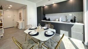 A modern kitchen with dark cabinets, a white countertop, and a dining area with a white table set for four. - AM2212 DOWNTOWN MIAMI, GREAT VIEWS STUDIO (Miami)