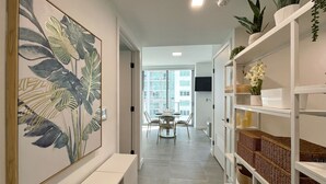 A modern interior with a large botanical print on the wall, a white bench, and a shelving unit with wicker baskets. - AM2212 DOWNTOWN MIAMI, GREAT VIEWS STUDIO (Miami)