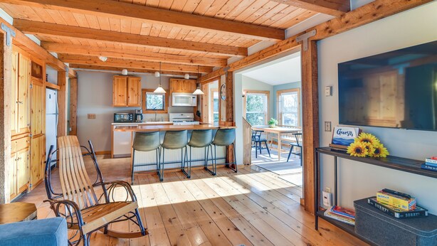 Una cocina amplia con vigas de madera, una barra y una zona de estar con sillas.