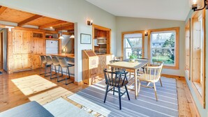 Una cocina amplia con armarios de madera, un comedor con mesa y sillas, y ventanas grandes que dejan entrar luz natural.