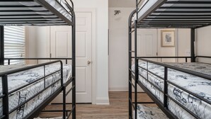 A room with bunk beds, a door, and a framed picture on the wall.