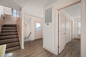A spacious hallway with a wooden staircase, white doors, and a vent on the wall. - The Gorbals:Oceanside, pool, hot tub, close to the beach & Wright Bro's Memorial (Kill Devil Hills)