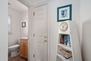 A bathroom with a toilet, wooden cabinet, and a white door.