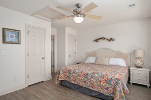 Una camera da letto con un letto, una ventola a soffitto, un comodino e un elemento decorativo a parete.