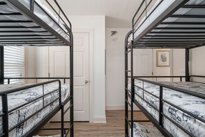 A room with bunk beds, a white door, and a framed picture on the wall.