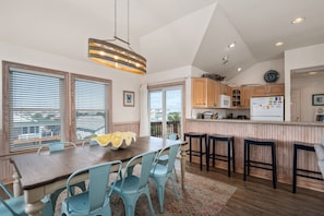 A modern kitchen with a dining area, wooden cabinets, and a bar counter.