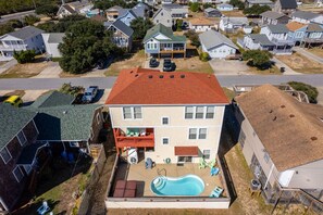 A two-story house with a swimming pool, a covered patio, and a fenced backyard.