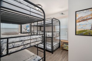 A bunk bed room with a poster on the wall and a ceiling fan.