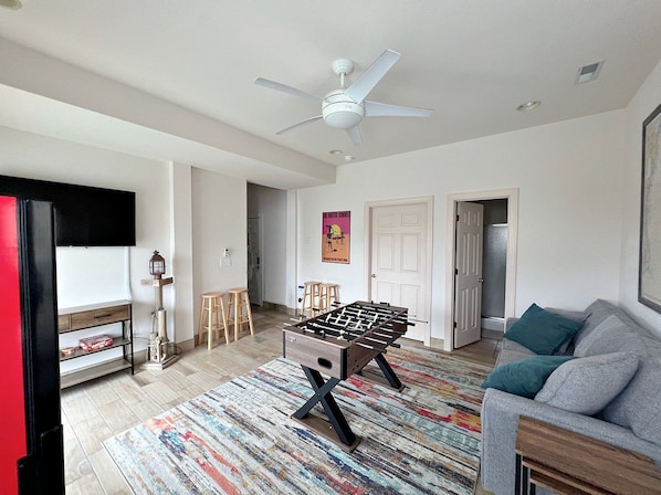 A living room with a foosball table, a ceiling fan, and a sofa.