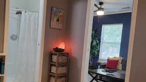 Una habitación con suelo de madera, un calentador, un espejo, una puerta y una ventana con persianas.