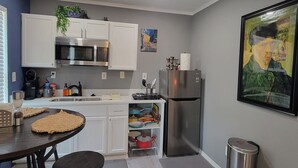 Una cocina moderna con armarios blancos, electrodomésticos de acero inoxidable y suelo gris.