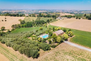 Vista aérea de una propiedad rural con piscina, rodeada de campos y árboles.