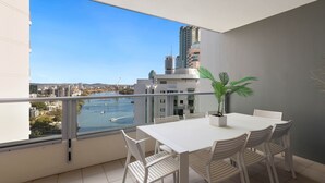 A balcony with a white table and chairs, a potted plant, and a view of a cityscape and water. -  Skyline hosted by AAB (Brisbane)