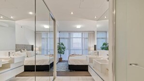 A modern hotel room with a large bed, a separate seating area, a small balcony, and a large mirror. -  Skyline hosted by AAB (Brisbane)