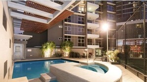 An indoor swimming pool with a sunken hot tub, surrounded by a modern building with balconies and a covered patio area. -  Skyline hosted by AAB (Brisbane)