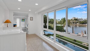 Ein geräumiger Flur mit großen Fenstern, die einen Pool und Wasserblick bieten, weißen Wänden und einer Decke mit Einbuchtungslampen.