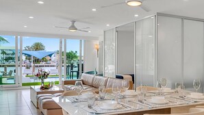 Un comedor con una mesa grande preparada para una comida, un sofá y vistas a una piscina y un área de estar exterior.