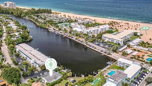 Vista aérea de un complejo turístico frente al mar, con un puerto deportivo, playa y vistas al océano.