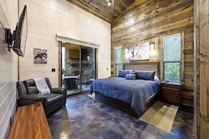 A bedroom with a bed, a sofa, a TV, and a fireplace. - EV Outlet , Hot Tub, Firepit, Playset, Pool Table, Creek (Broken Bow)