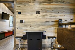A compact RV interior with a kitchenette, two bar stools, a small table, and a metal sink. - EV Outlet , Hot Tub, Firepit, Playset, Pool Table, Creek (Broken Bow)