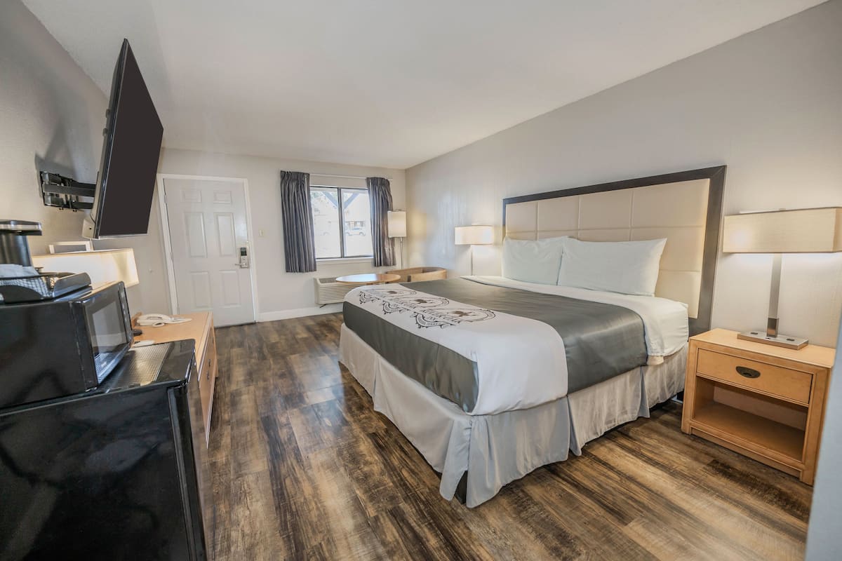 A hotel room with a bed, bedside tables, a TV, and a microwave.