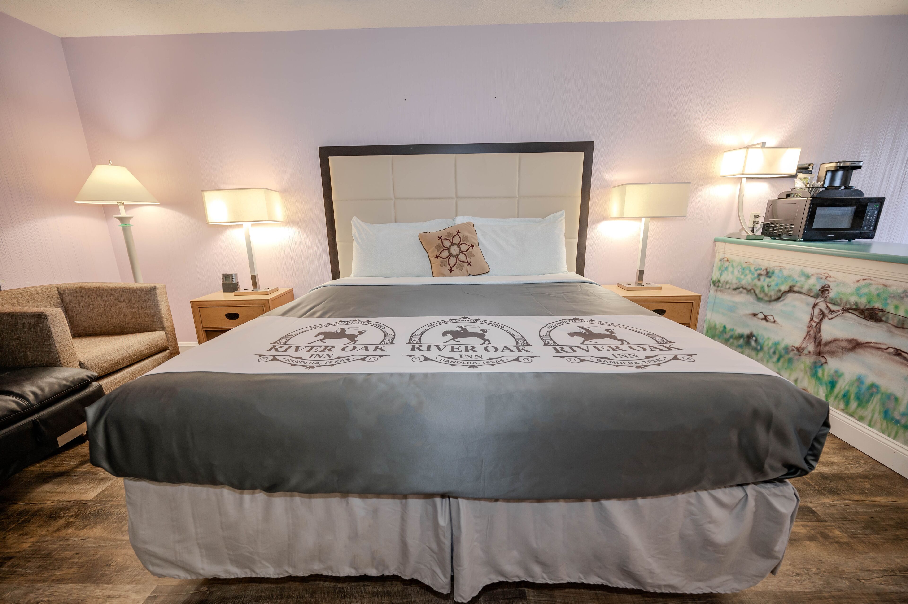 A hotel room with a large bed, two bedside lamps, a coffee maker, and a couch.