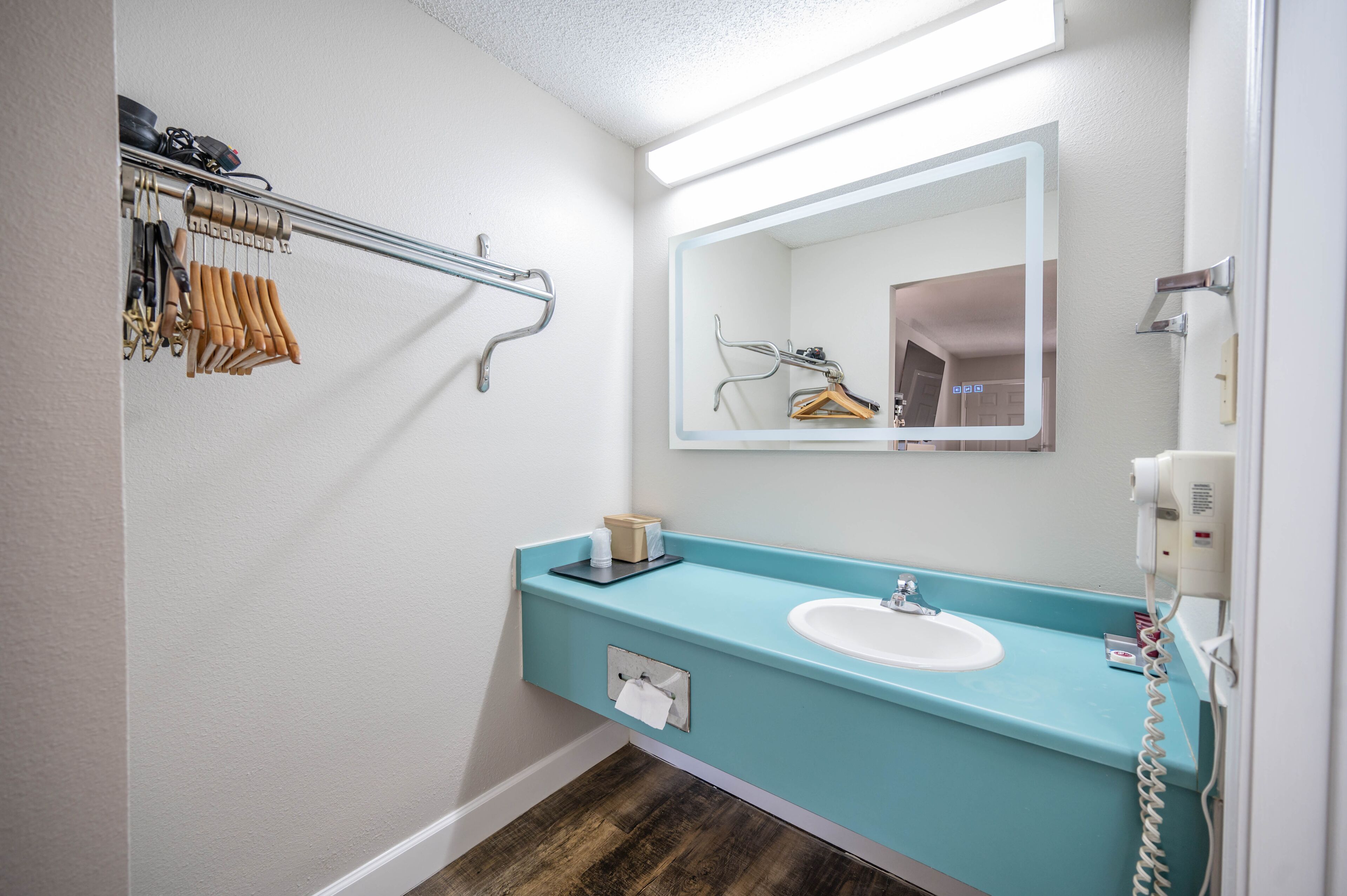 A bathroom with a white sink, a mirror, a towel rack, and a hairdryer.