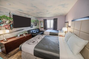 A hotel room with a large bed, a desk, a chair, a television, and a mural on the wall.