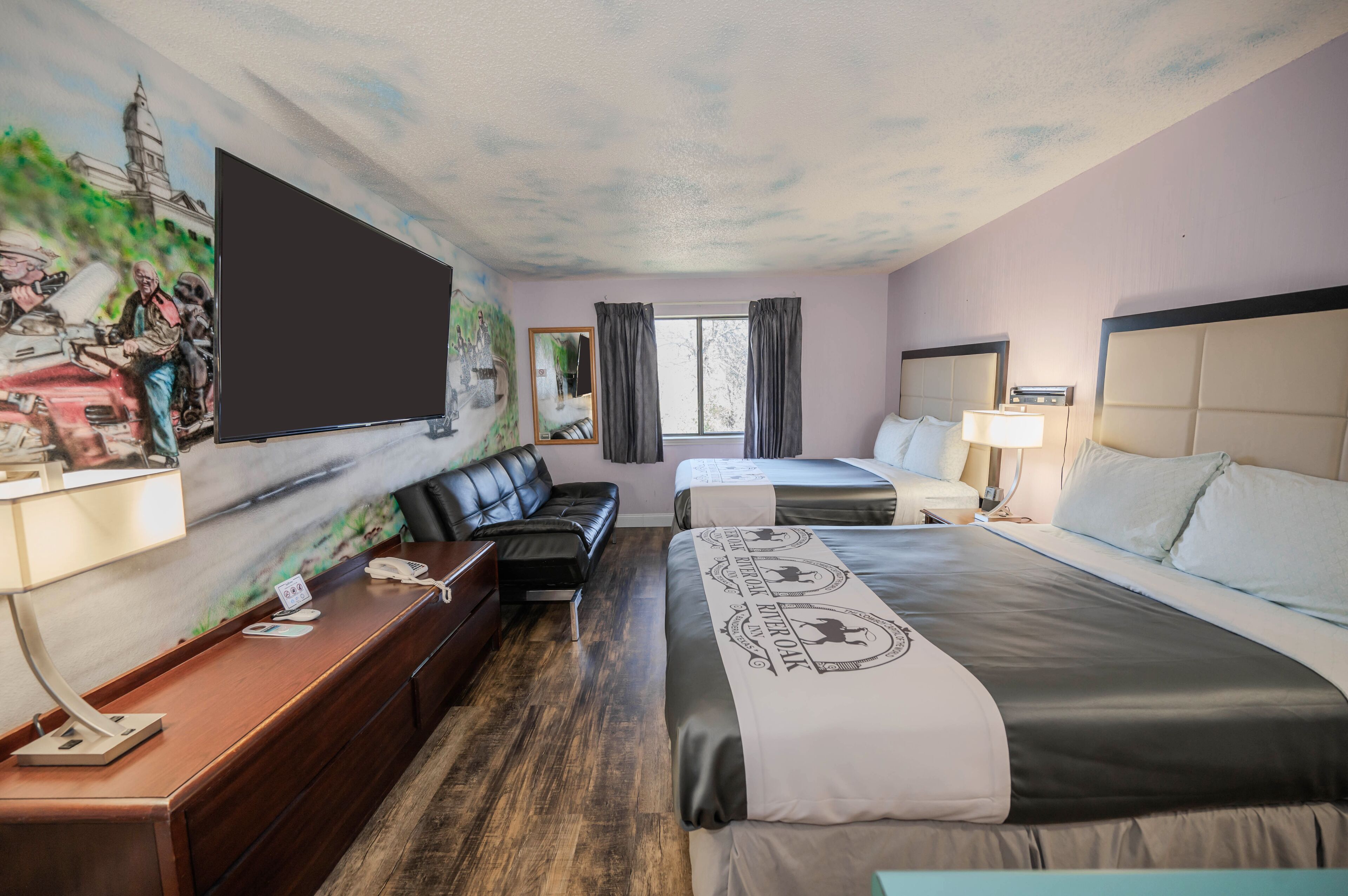 Een hotelkamer met een groot bed, een bank, een bureau met telefoon en een televisie.