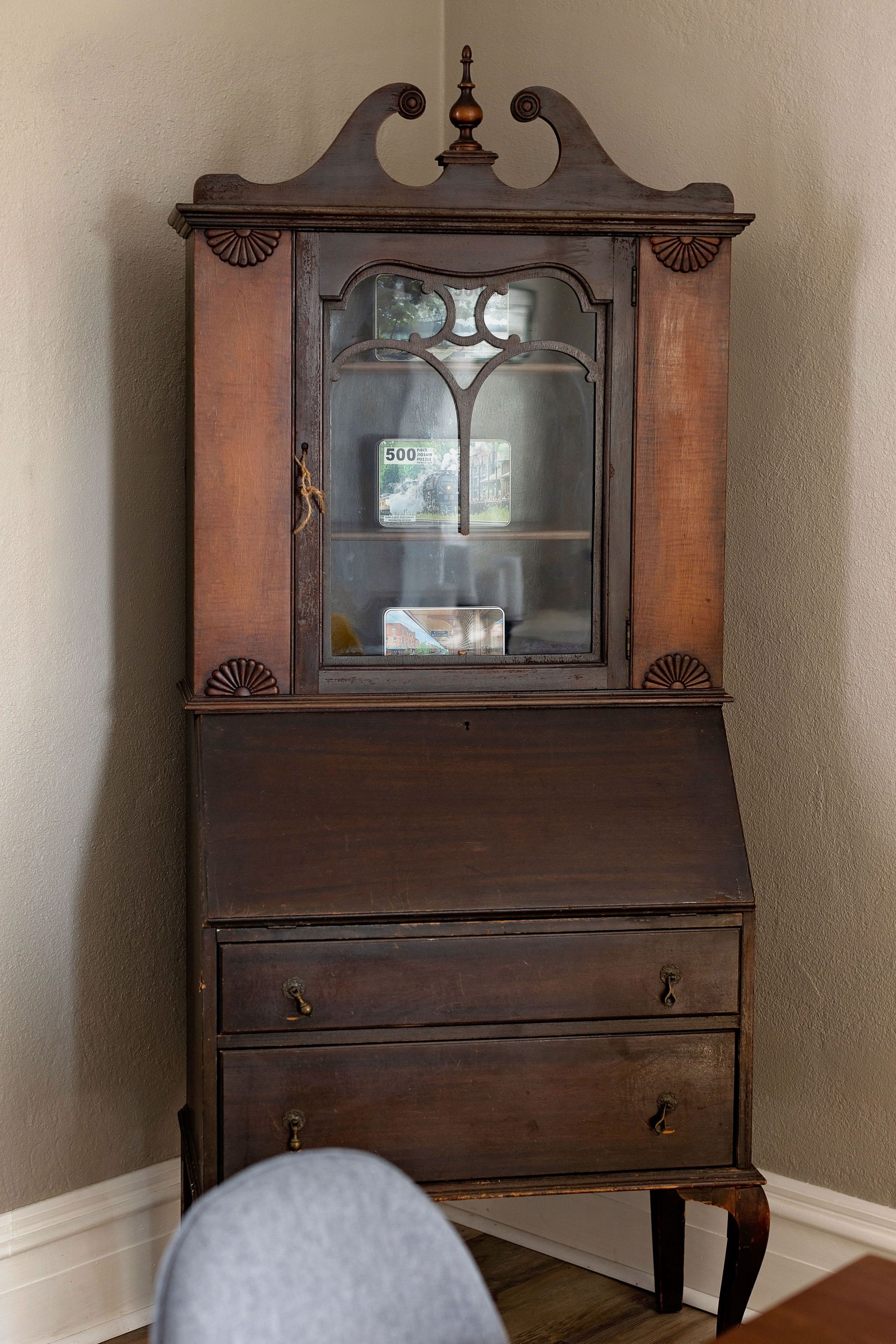 A dark wooden cabinet with a glass door and two drawers.