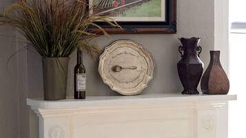 A fireplace mantel with a framed train painting, a wine bottle, and decorative vases.