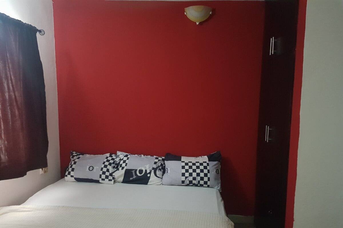 A room with a bed, red walls, a white ceiling, and a door.