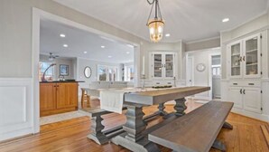 A spacious kitchen with a large island, wooden cabinetry, and a hanging light fixture. - Charming beach home, complete with pool & cozy guest house! (Clinton)