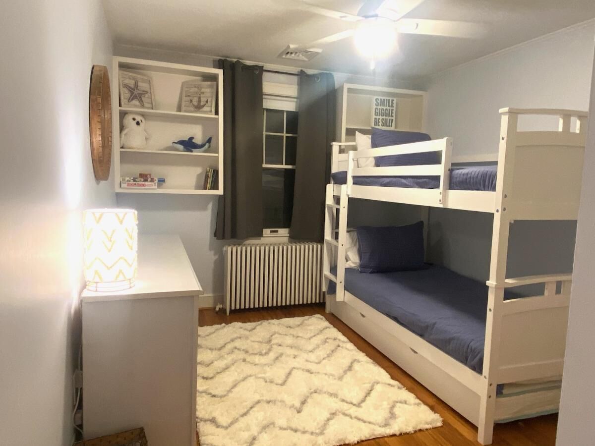 A bunk bed room with a desk, shelves, and a radiator.
