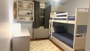 A bunk bed room with a desk, shelves, and a radiator.