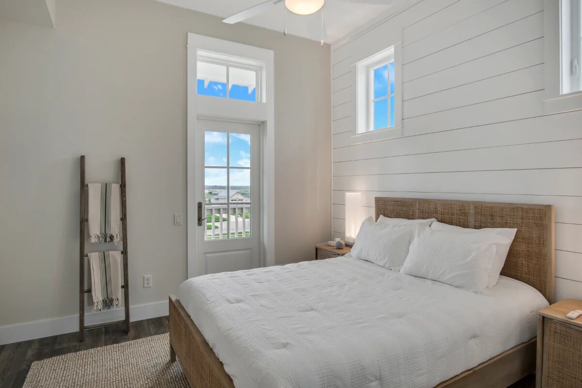 Ein Schlafzimmer mit einem großen Bett, einer Holzleiter, einer weißen Tür und einem Fenster.