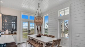 A modern kitchen with a large island, white cabinetry, and a hanging chandelier. - Shared Heated Pool, Golf Cart Boardwalk to Beach (Port Aransas)