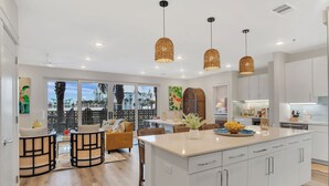 Una cocina moderna con armarios blancos, una isla central e iluminación colgante.