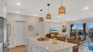 Una cocina moderna con armarios blancos, una isla central e iluminación colgante.
