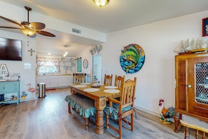Uma área de refeições com mesa de madeira, cadeiras e ventilador de teto.
