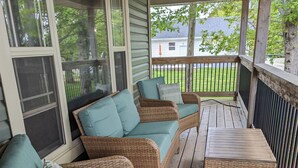 Eine überdachte Veranda mit Korbmöbeln und einem Tisch.