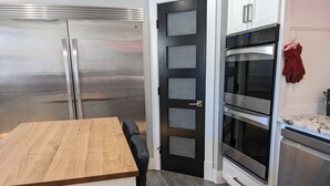 A modern kitchen with a stainless steel refrigerator, double oven, and wooden countertop.