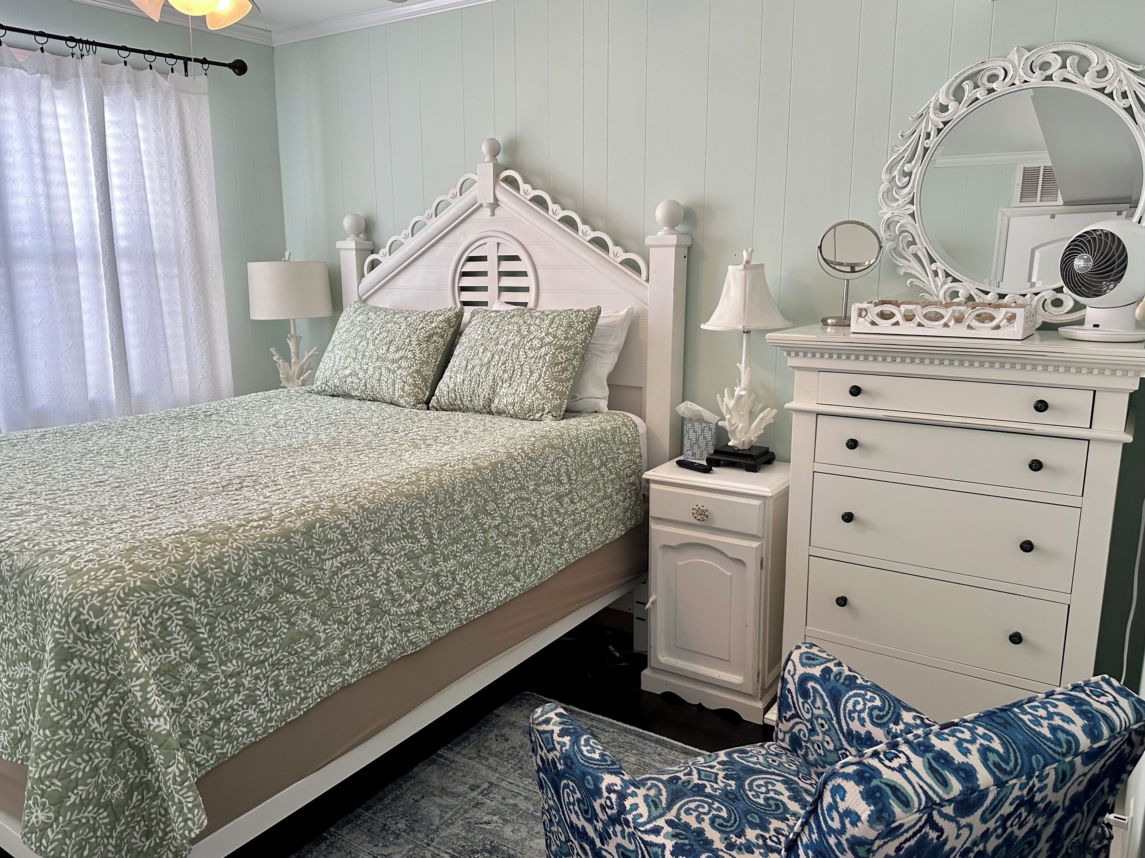 A bedroom with a bed, nightstands, a dresser, a mirror, and a patterned rug.