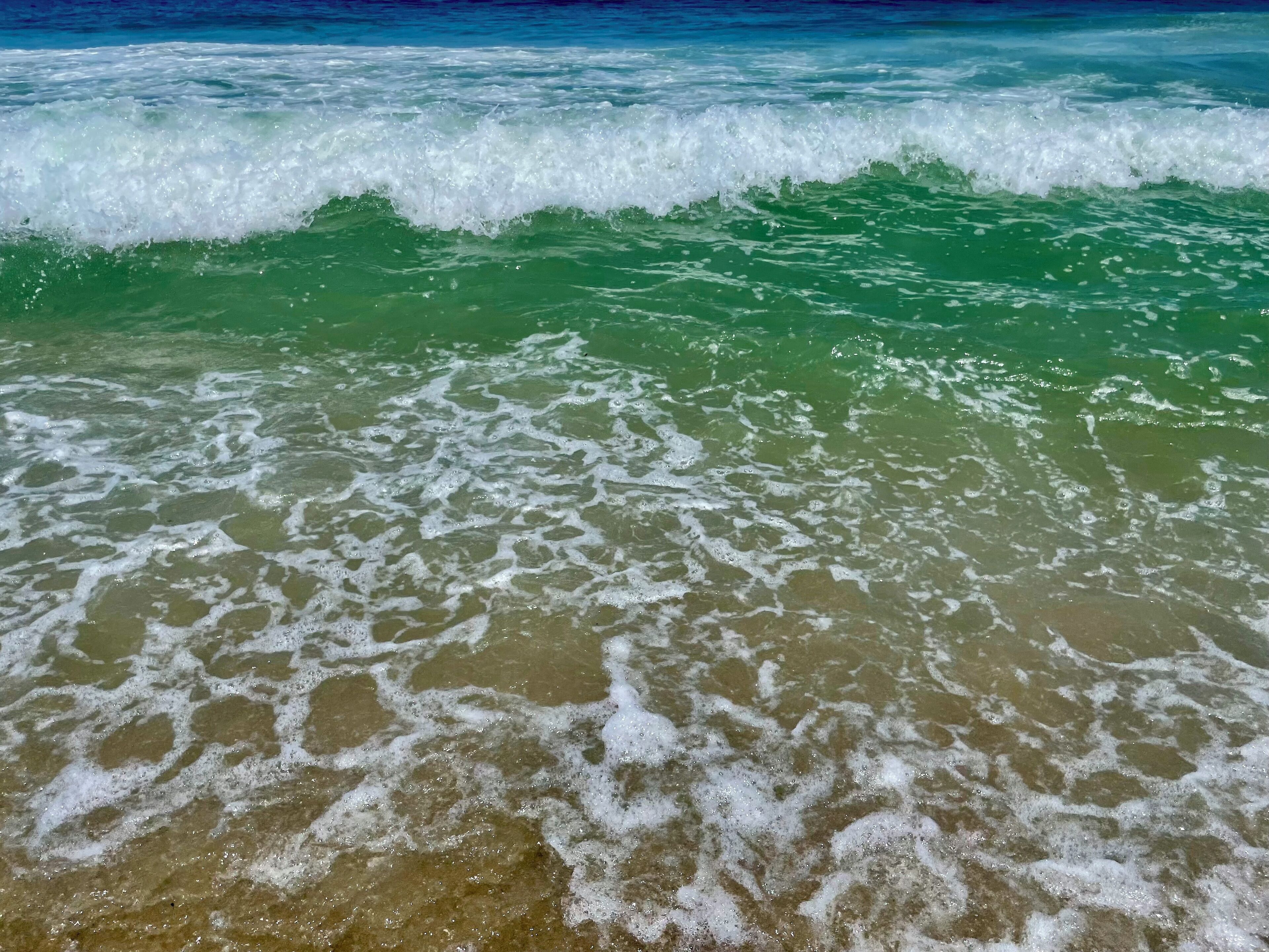 A beach with waves and clear water.