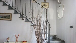 A staircase with a metal railing, a white console table with decorative items, and a vase with branches. - Lovely apartment for 4 guests with A/C, WIFI, TV, terrace and pets allowed (Capannori)